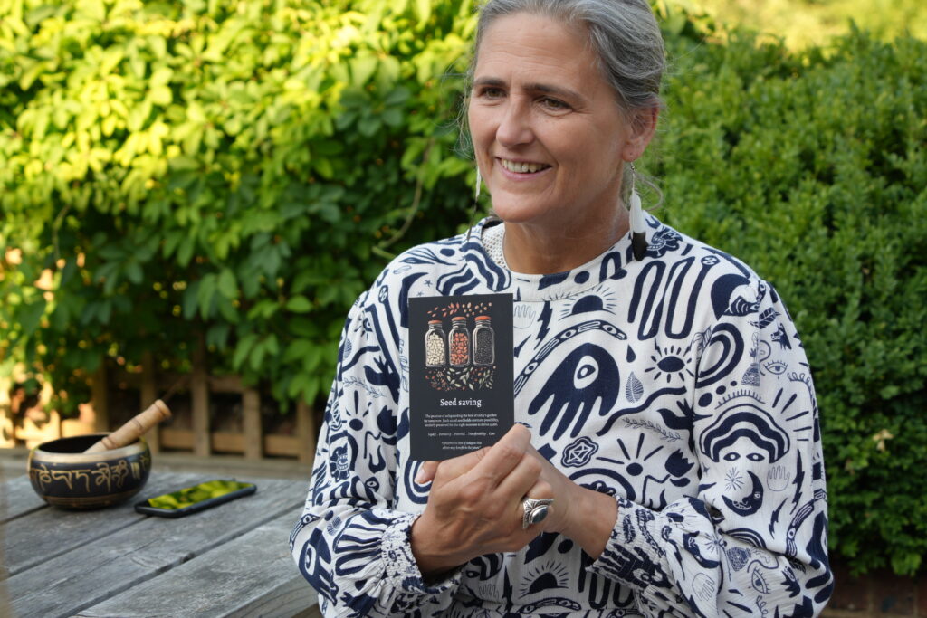 Tanja Kerlo holding a card with the words 'seed saving' written on it.