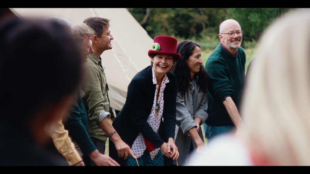 A woman in a red top hat smiles at the camera amongst a wider group of people.