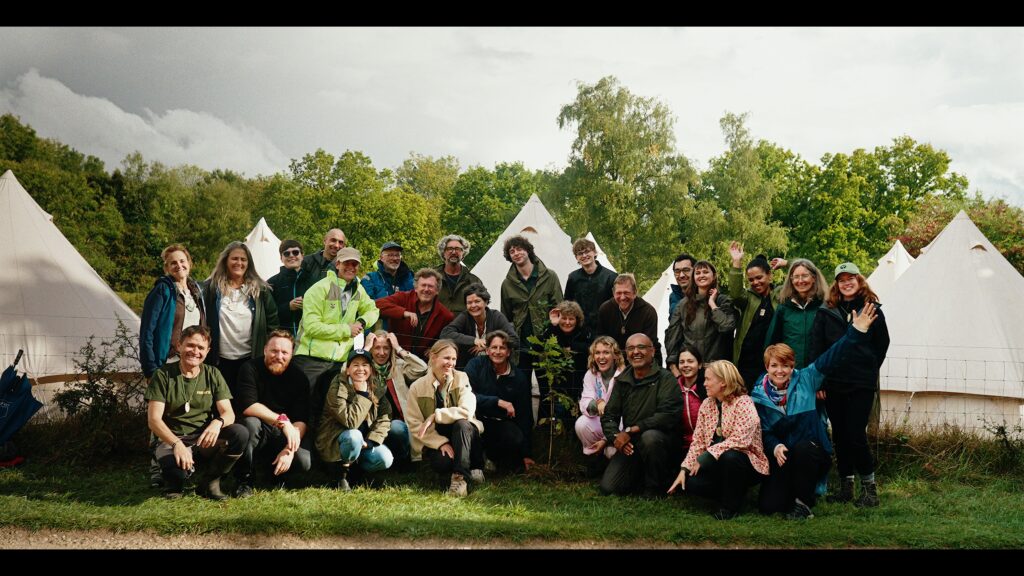 A group of people gathered around a sapling tree, freshly planted.