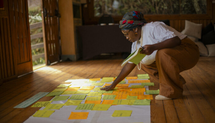 A Woman Arranges A Variety Of Post-it Notes On A Large Sheet Of Paper Over A Wooden Floor.